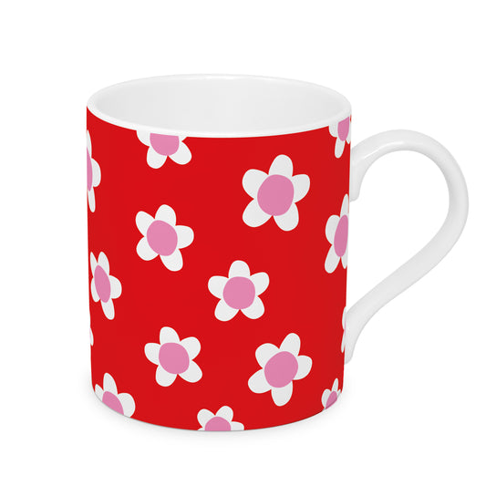 Eine rote Porzellantasse mit einem weißen und rosafarbenen Blumenmuster.