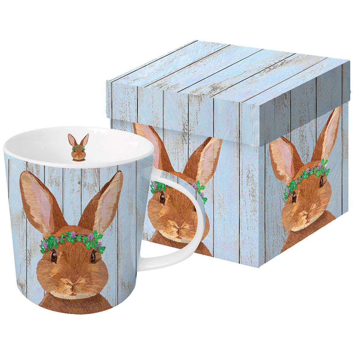 Porzellantasse mit Hasenmotiv und passender Geschenkdose auf hellblauem Holzoptik-Hintergrund.